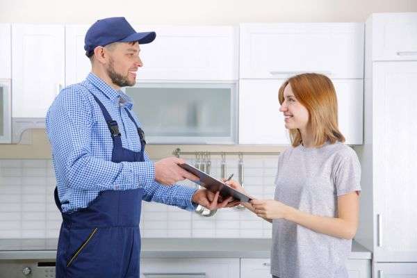A plumber showing a redheaded woman information on a clipboard